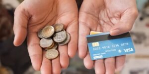 Deux mains comparant des pièces de monnaie et une carte bancaire.